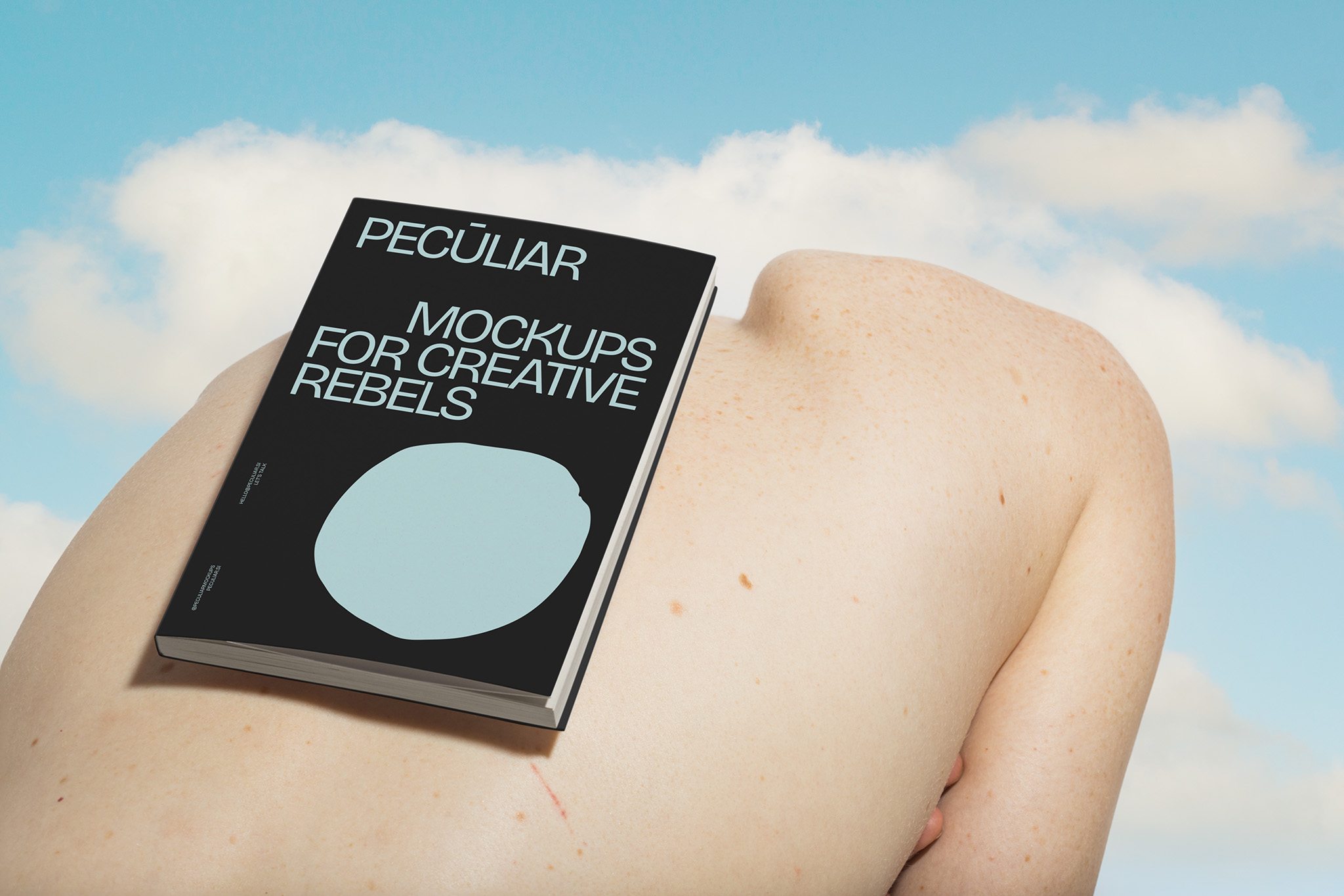 Slouched back bodyscape featuring an A5 book softcover mockup, set against a cloudy blue sky, in use example.