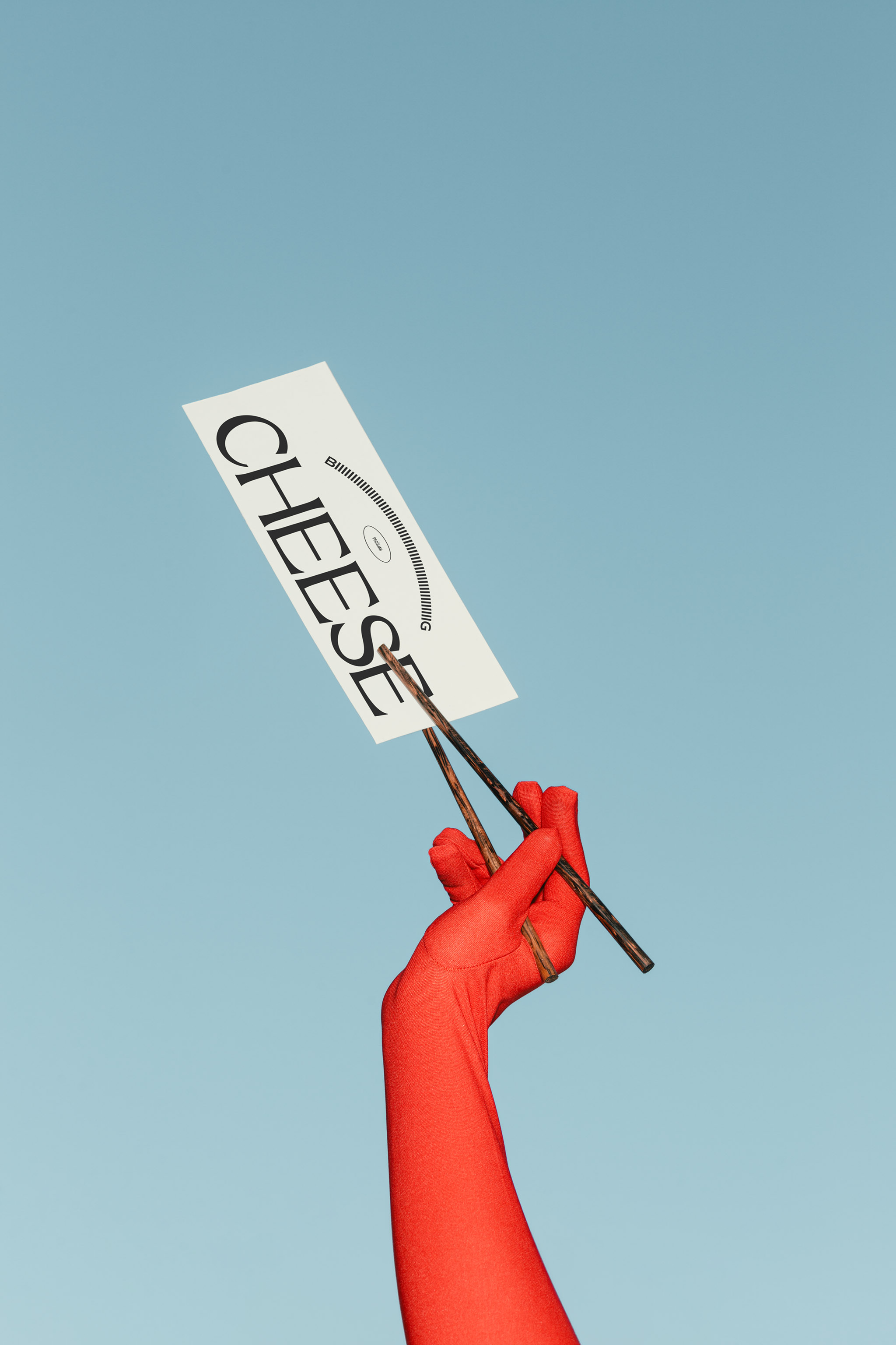 Photo of a red gloved hand, set against a light pastel blue sky, holding up a vertical paper menu with black typography with dark wooden chopsticks, in use example.