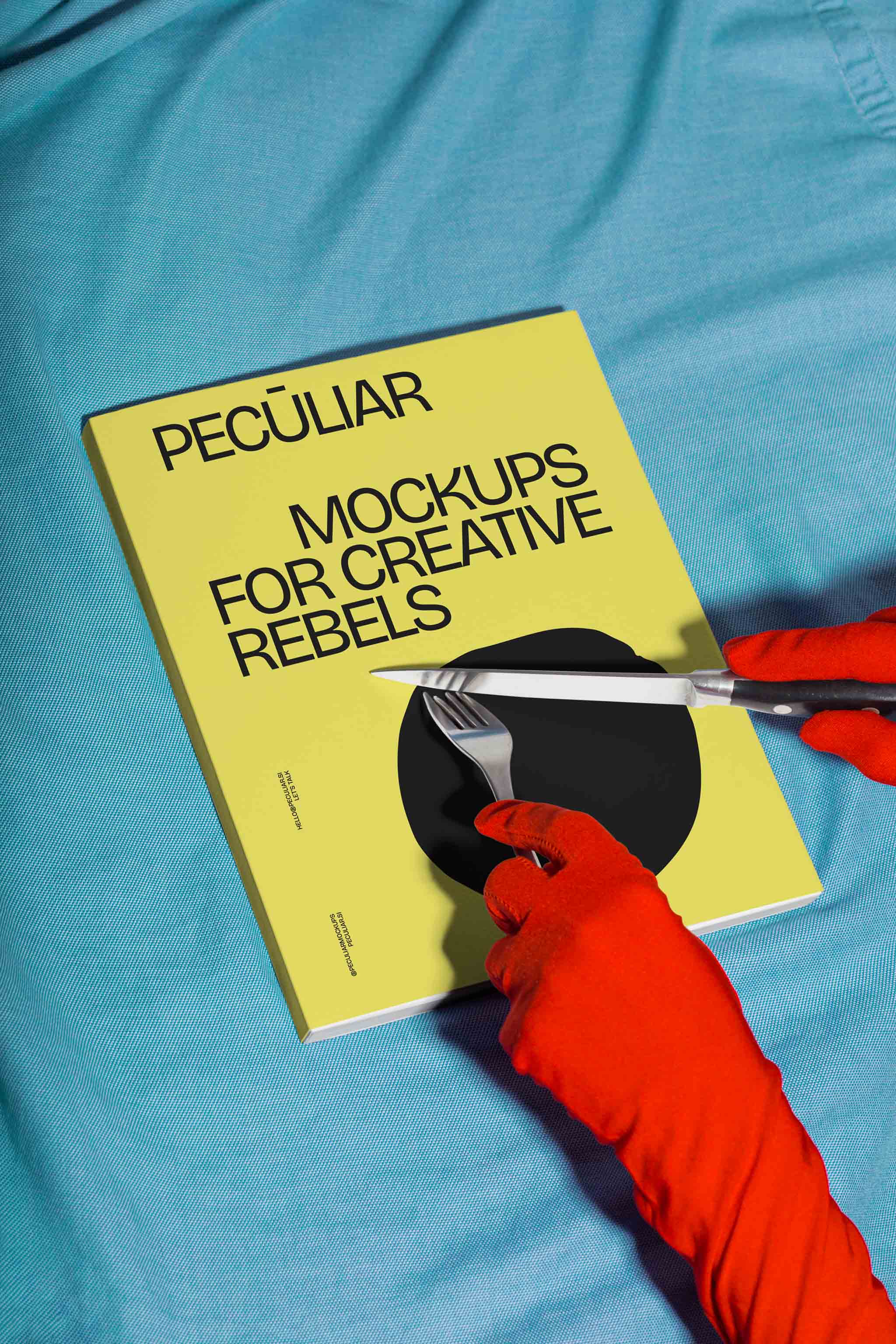 Two gloved hands holding utensils over a book cover mockup set against blue fabric, in use example alternative colors.