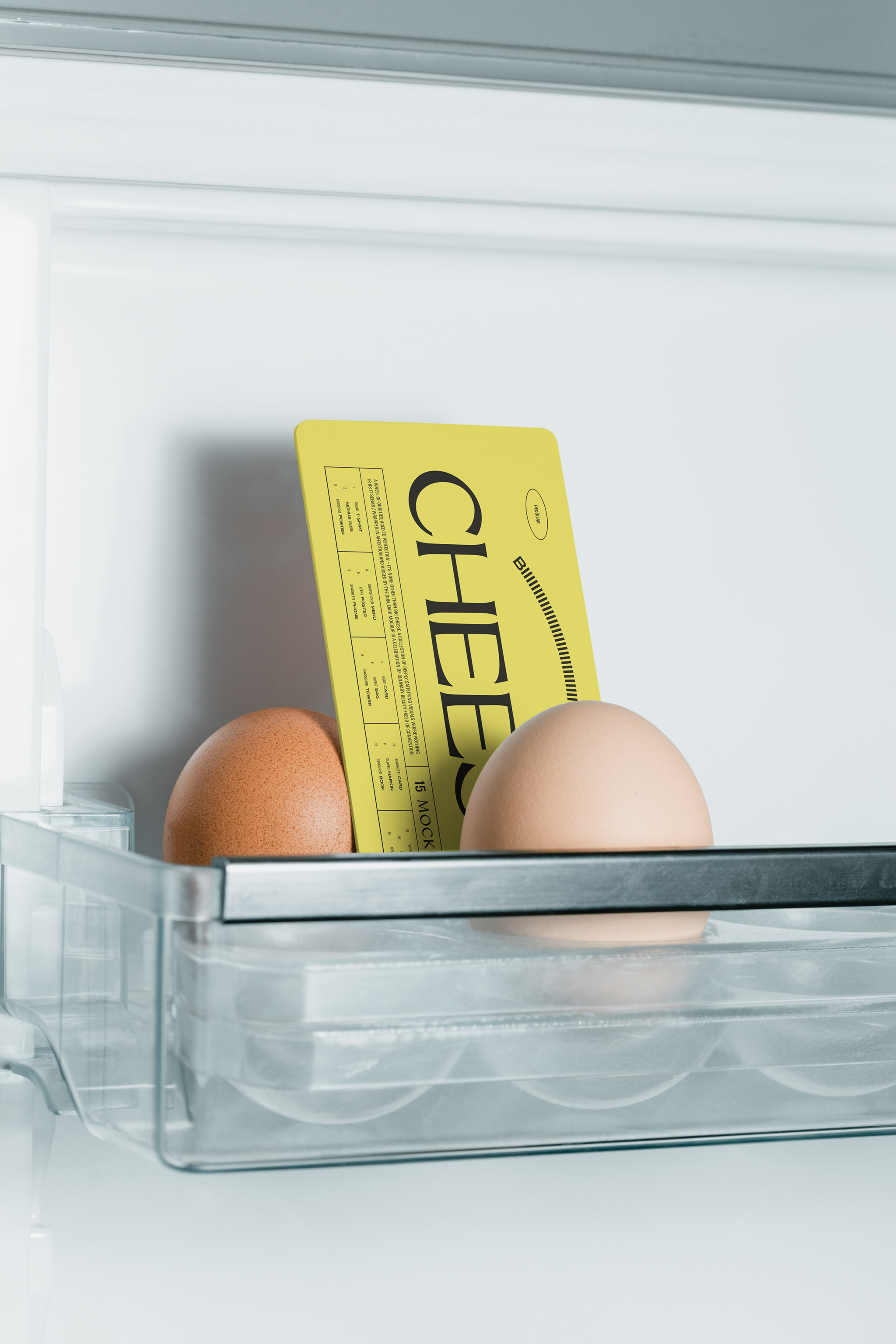 Close-up photo of two eggs in a minimalist white fridge among which a vertical american business card mockup with dark typography is placed, in use example.