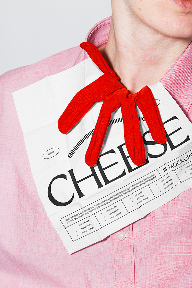 Close-up photo of a person in a pink dress shirt on top of which a white napkin print mockup with black lettering and a red glove are tucked, in use example.