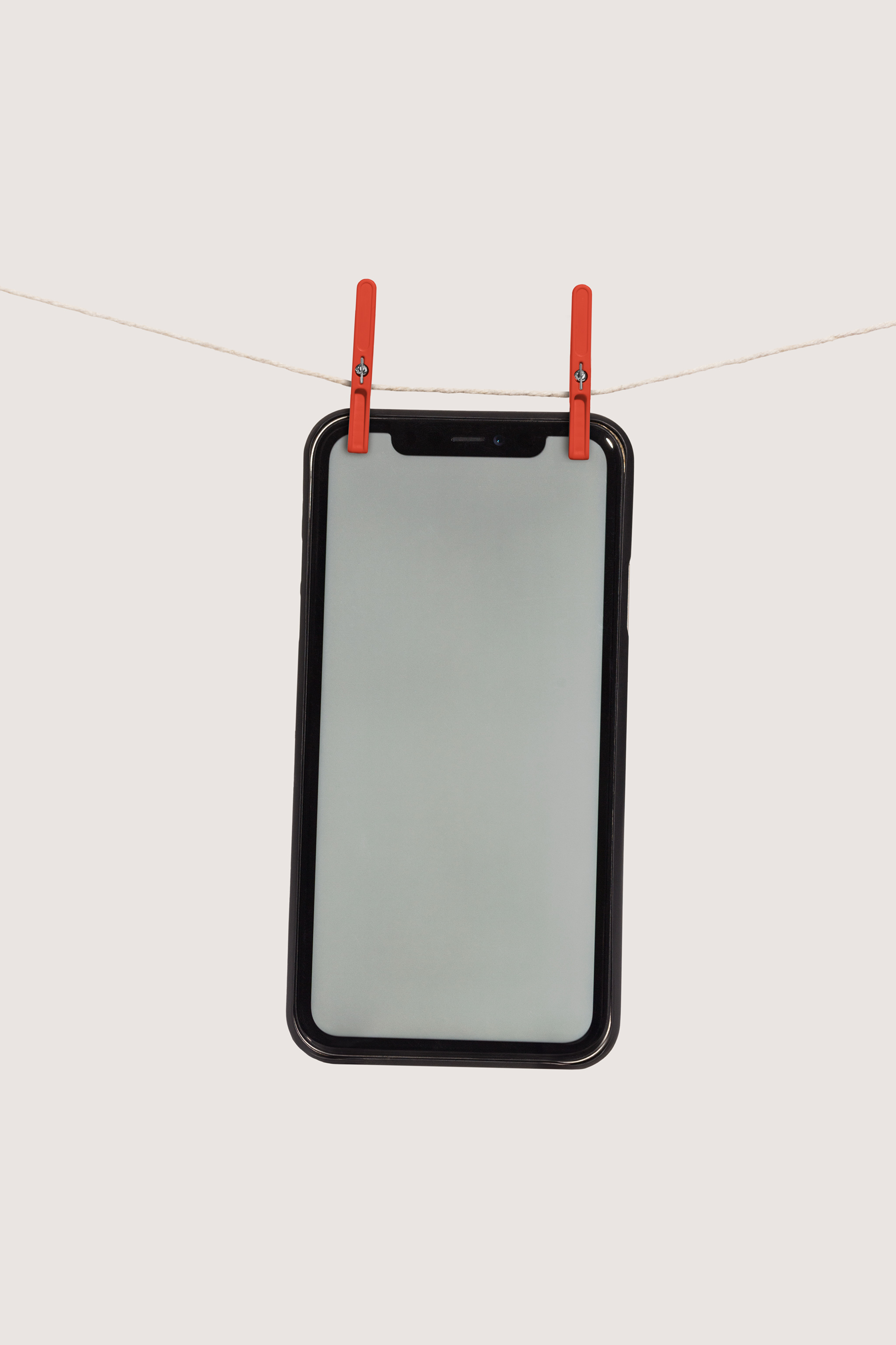 Large floating iPhone device mockup hung with clothespins in the air against a cloudy sky background, empty mockup.